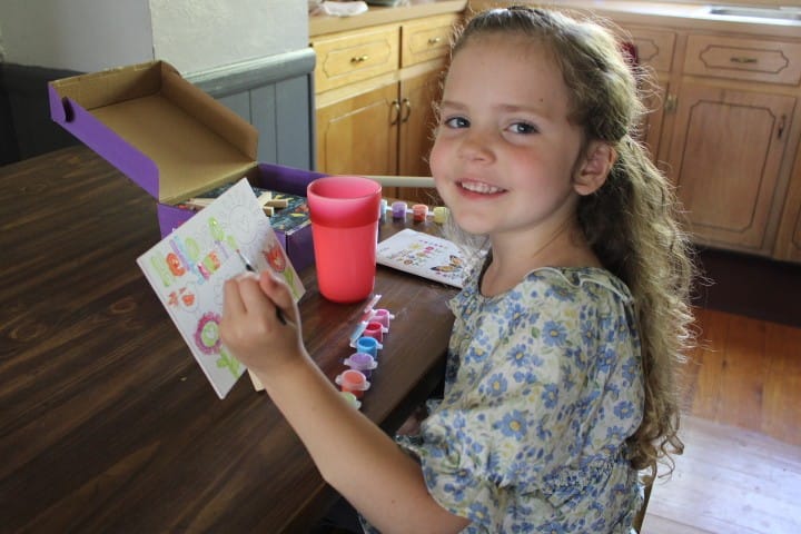 5 year old girl paints on a prestamped canvas.