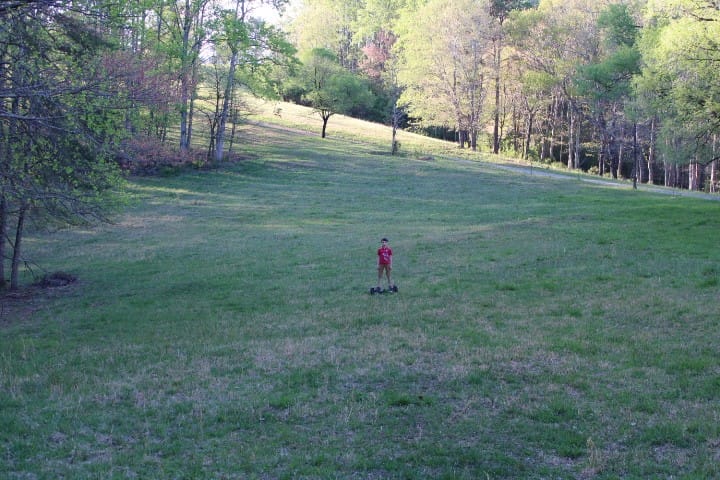 7 year old boy rides a hoverboard through an open field in early spring