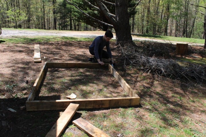 teen boy makes a raised garden bed out of old wood