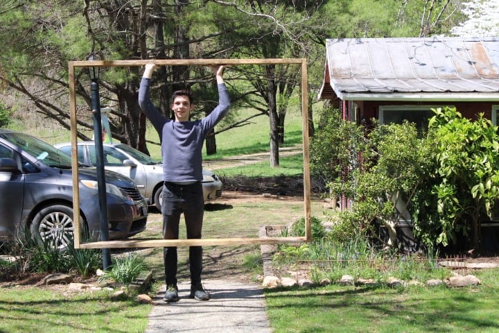 teen boy holds his garden box up around him like a picture frame