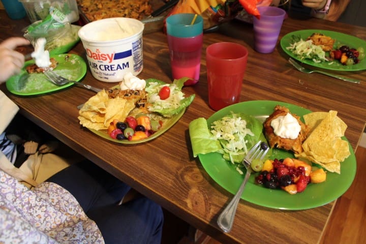 colorful plates full of a birthday dinner: enchilada casserole and fruit salad