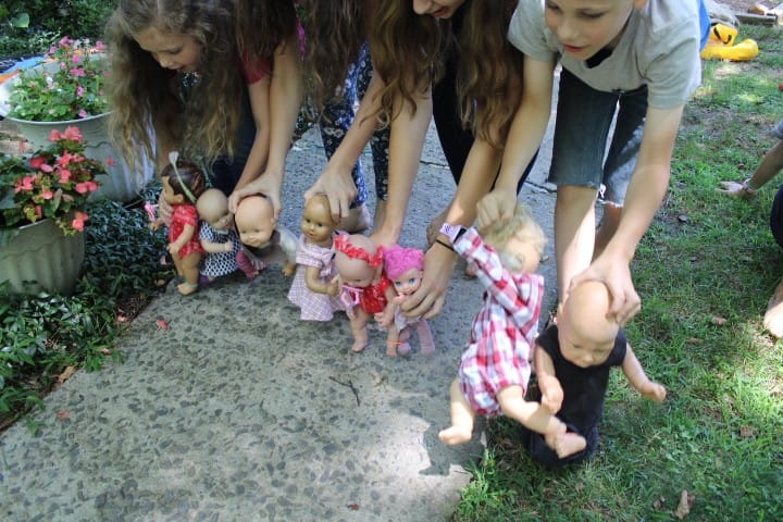 5 siblings do a three legged race with their dolls