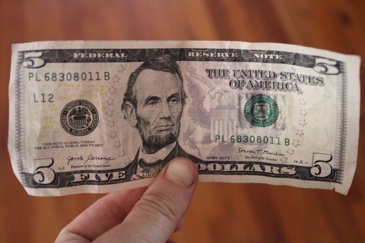 holding up a five dollar bill