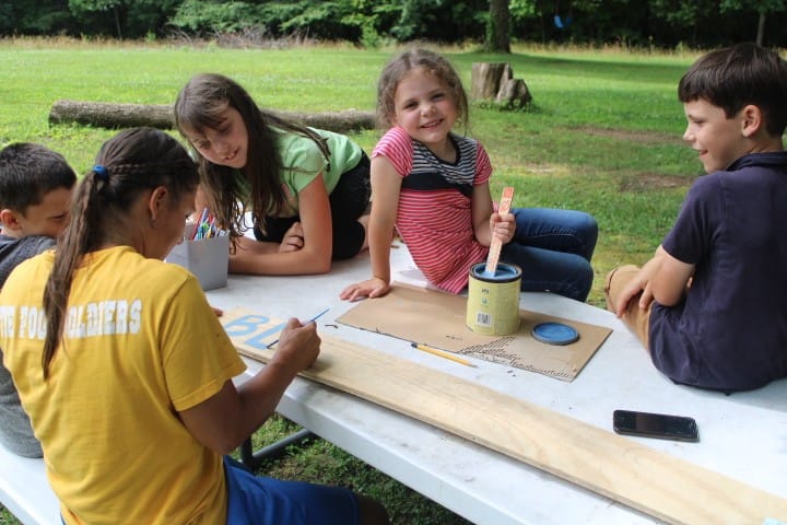 kids make a blueberry sign for a blueberry patch on a picnic table